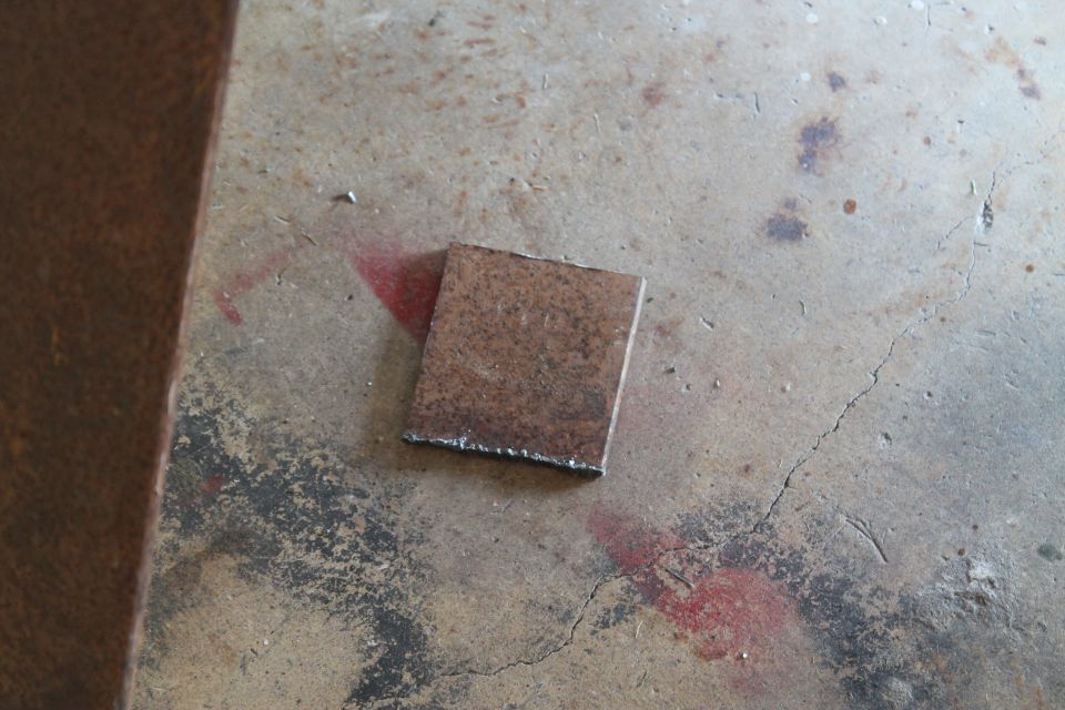 Square metal plate with rough edges on a concrete floor