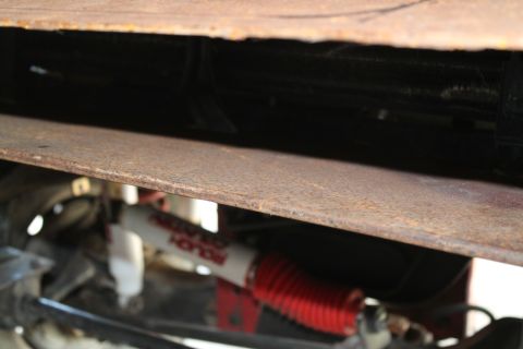 1990 Ford Bronco - A close-up view of a vehicle's undercarriage reveals a rusty metal component and a shock absorber.