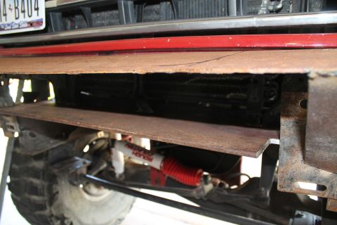 1990 Ford Bronco - Custom steel plate bumper and red Rough Country shock absorber visible on a vehicle's front end.