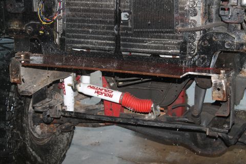 1990 Ford Bronco - The front suspension and bumper assembly of a 1990 Ford Bronco, showing aftermarket shocks and a custom bracket.