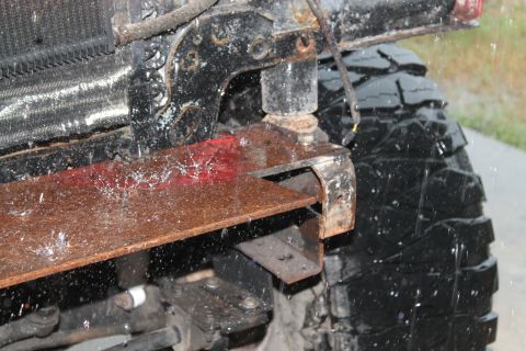 1990 Ford Bronco - Close-up of a custom bumper bracket and a large tire, with water splashing.