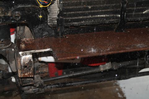 1990 Ford Bronco - Close-up of a rusted metal plate attached to the vehicle's frame, with visible wiring and radiator components.