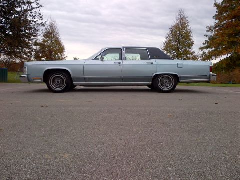 2001 Ford Crown Victoria - A side view of a light blue 1980s Lincoln Town Car with a black vinyl roof.