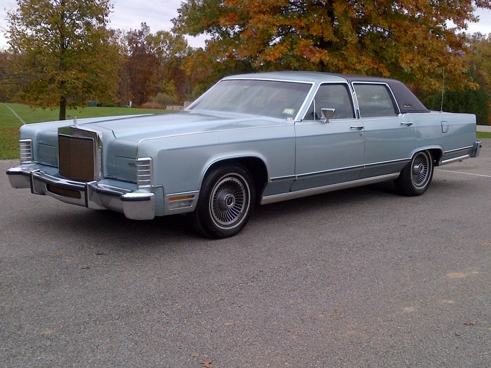 Light blue Lincoln Continental sedan with a black vinyl roof, parked on asphalt