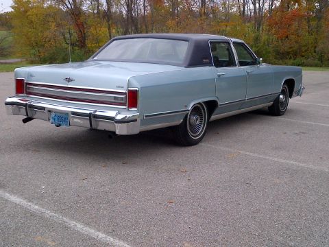 2001 Ford Crown Victoria - This classic Lincoln Continental is seen from the rear three-quarter view on a paved surface with trees in the background.