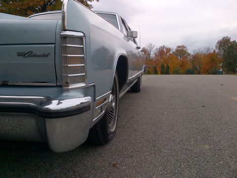 2001 Ford Crown Victoria - Rear view of a light blue Lincoln Continental, showing its distinctive taillight and chrome bumper.