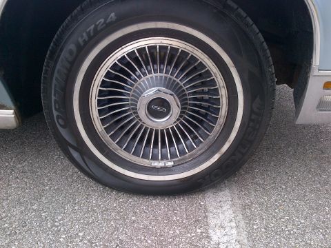 2001 Ford Crown Victoria - This image shows a close-up of a Lincoln wheel, a distinctive chrome hubcap and a whitewall tire, with visible tire brand text.