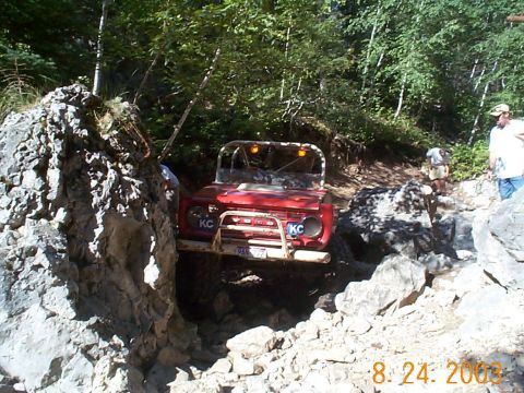 1977 Ford Bronco - A red 1977 Ford Bronco navigates a challenging rocky terrain on an off-road trail.