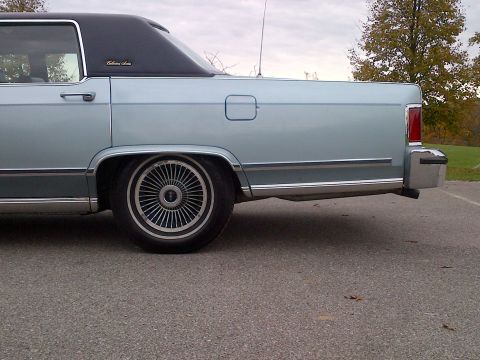 2001 Ford Crown Victoria - Side view of a light blue sedan a black vinyl roof and distinctive wire wheels.