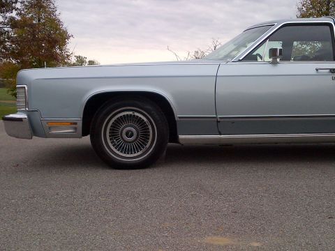 2001 Ford Crown Victoria - This light blue sedan features a distinctive chrome bumper and classic wire wheels.
