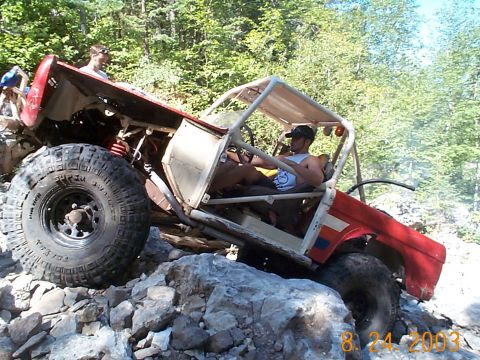 1977 Ford Bronco - Modified off-road vehicle navigates a rocky trail with a driver and passenger inside.