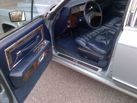 2001 Ford Crown Victoria - The interior of a classic Lincoln Continental features luxurious blue leather seats and wood accents on the door panel.