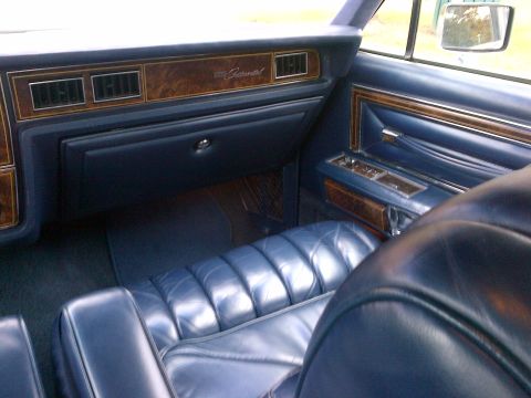 2001 Ford Crown Victoria - The interior features plush blue leather seats and classic wood grain trim on the dashboard and door panels.