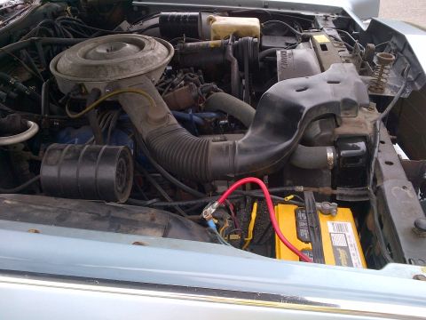 2001 Ford Crown Victoria - The engine bay of a car is visible, an air cleaner, hoses, and a yellow battery.