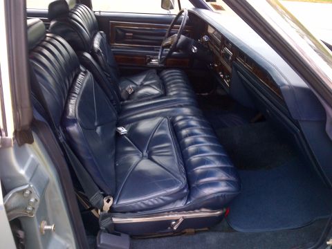 2001 Ford Crown Victoria - The interior of a car features blue leather bench seats and wood trim on the dashboard.