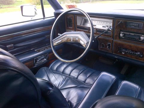2001 Ford Crown Victoria - The interior of a car features plush blue leather seats and faux wood trim on the dashboard and door panels.