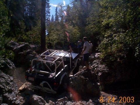 1977 Ford Bronco - An off-road vehicle tackles a challenging rocky terrain with spectators watching.