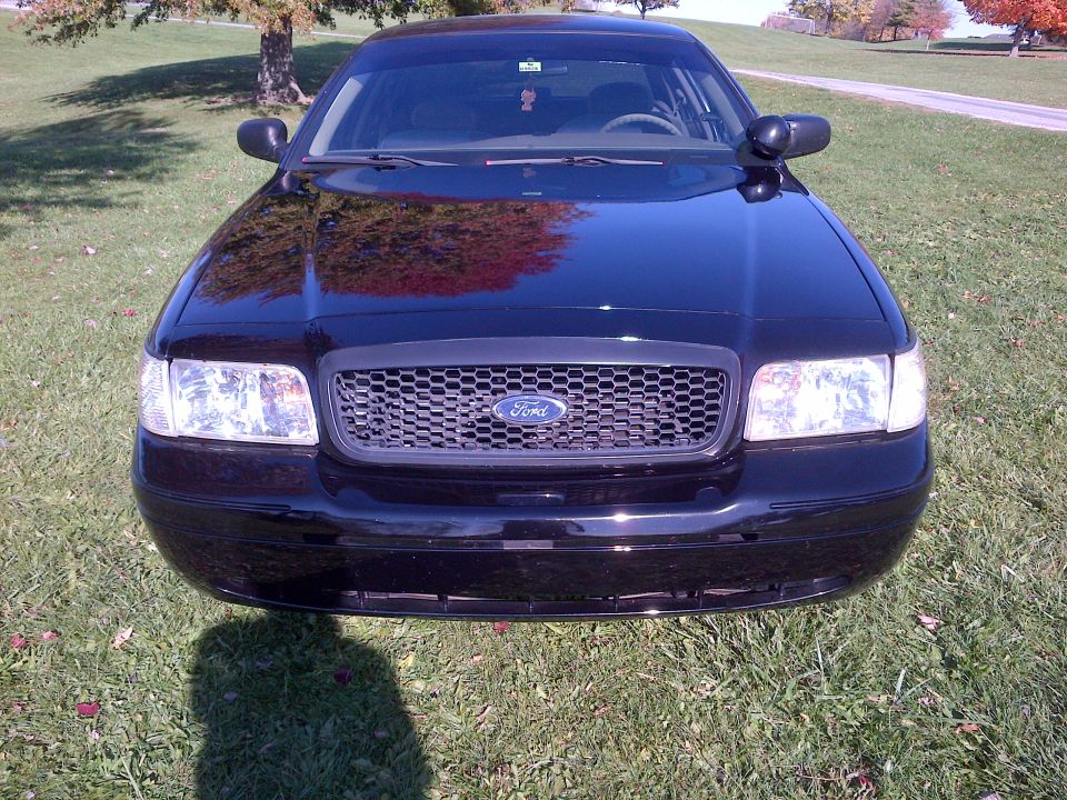 Black 2001 Ford Crown Victoria front view, parked on grass with trees in background