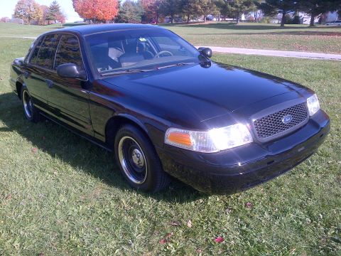 2001 Ford Crown Victoria - A black 2001 Ford Crown Victoria is parked on a grassy lawn with fall foliage in the background.