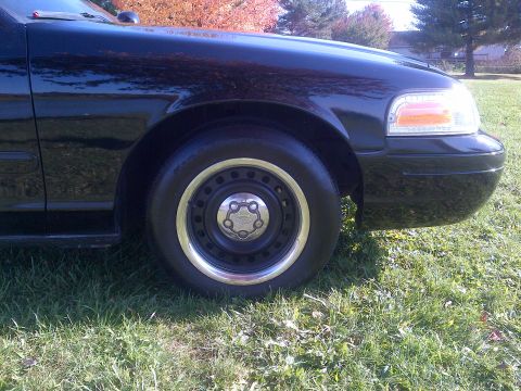 2001 Ford Crown Victoria - Front quarter view of a black 2001 Ford Crown Victoria showing the wheel and fender.