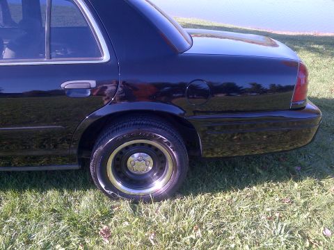 2001 Ford Crown Victoria - Rear view of a black 2001 Ford Crown Victoria, showing the quarter panel, bumper, and wheel.
