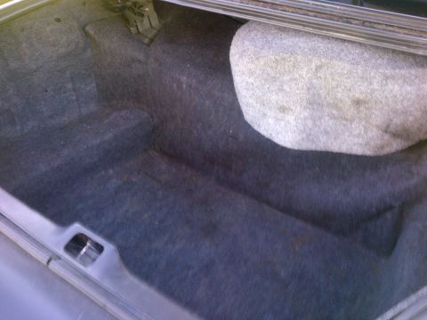 2001 Ford Crown Victoria - The trunk of a car is shown, dark carpeting and a spare tire. A website logo is visible in the corner.