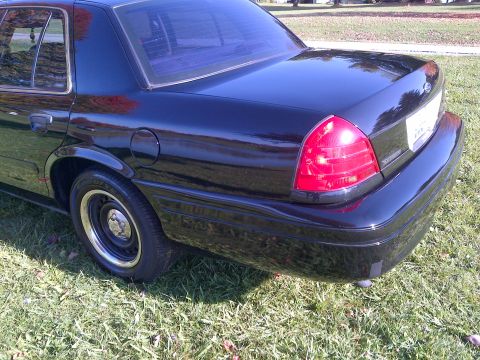 2001 Ford Crown Victoria - The rear passenger side of a black sedan is shown parked on a grassy area.