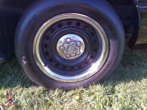 2001 Ford Crown Victoria - Close-up of a wheel on a black vehicle, a Ford logo on the hubcap.