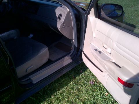 2001 Ford Crown Victoria - The interior of a 2001 Ford Crown Victoria is visible, with the driver's side door open to reveal the door panel and dashboard.