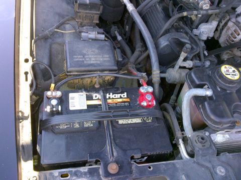 2001 Ford Crown Victoria - Close-up of a car battery and engine components, showing a Ford logo on a black electrical box.