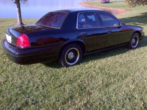 2001 Ford Crown Victoria - Black 2001 Ford Crown Victoria parked on a grassy area next to a lake.