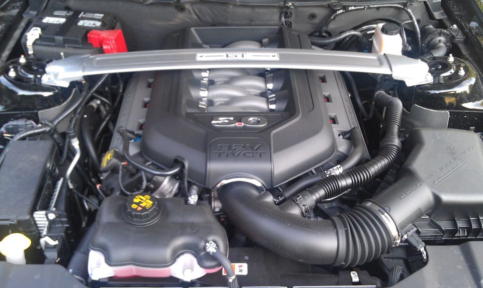 Ford Mustang 5.0L V8 engine with strut tower brace. "5.0" and "32V TI-VCT" visible on engine cover