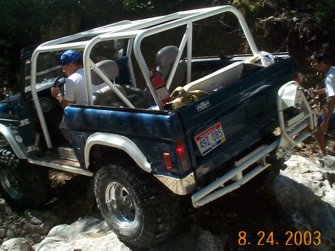 1977 Ford Bronco - This SUV is equipped with a roll cage and is navigating a rocky terrain.