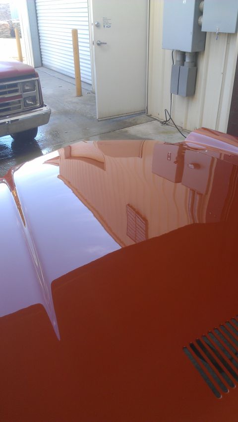 1973 Chevrolet Camaro - Reflection of a building and a red truck on the hood of an orange car.