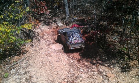 1987 Ford Bronco - An off-road vehicle with a custom roll cage tackles a challenging rocky path during an outdoor excursion.