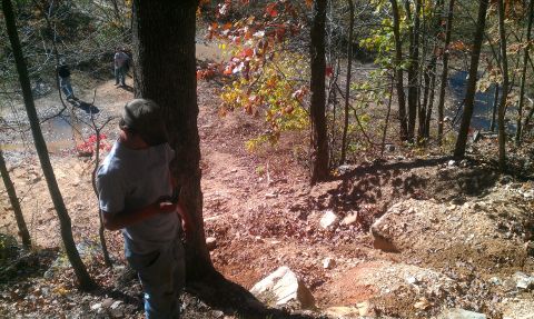 1987 Ford Bronco - People on an off-road trail in a wooded area with dirt and rocks.