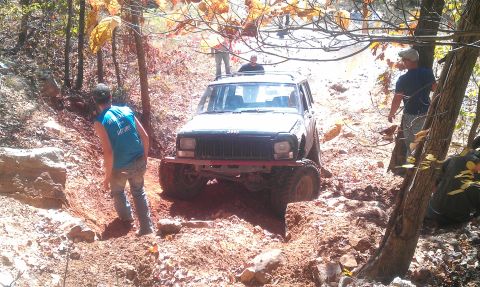 1987 Ford Bronco - A Jeep Cherokee XJ tackles a challenging muddy trail during an off-road excursion.