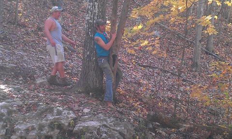 1987 Ford Bronco - Two men are in a wooded area with fallen leaves on the ground and trees with yellowing leaves.
