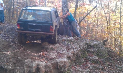 1987 Ford Bronco - Two men push a Jeep Cherokee XJ up a challenging rocky trail during an off-road trip.