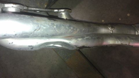 1973 Chevrolet Camaro - The underside of a vehicle shows two exhaust pipes, one slightly dented and showing signs of age.