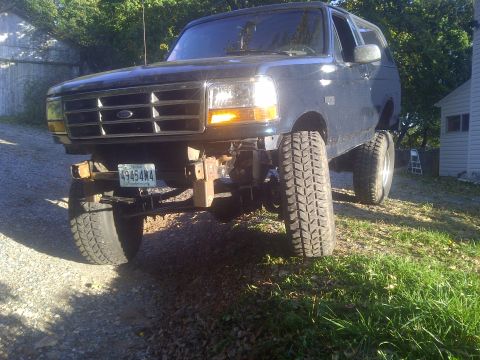 1995 Ford Bronco - A dark blue Ford Bronco with a lifted suspension and off-road tires is parked outdoors.