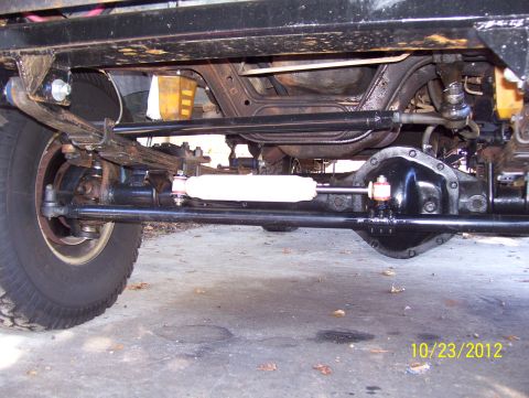 1990 Ford Bronco - Undercarriage view of a vehicle's front axle and steering components.