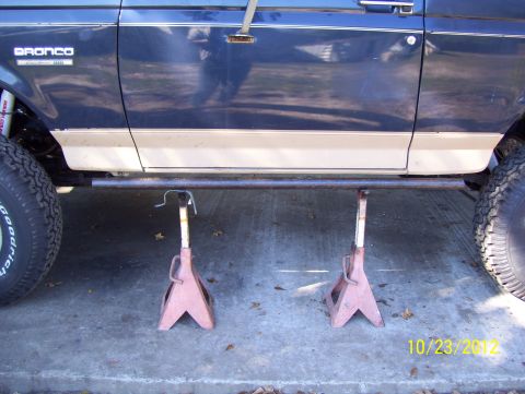 1990 Ford Bronco - Side view of a blue and tan SUV, identified as a Bronco, resting on jack stands.