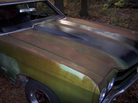 1970 Chevrolet Chevelle - A rusty green 1970 Chevrolet Chevelle SS sits outdoors with a black hood stripe and visible SS badging.