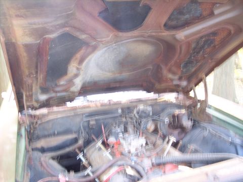 1970 Chevrolet Chevelle - The underside of a car's hood shows significant rust, with a blurry view of the engine bay below.