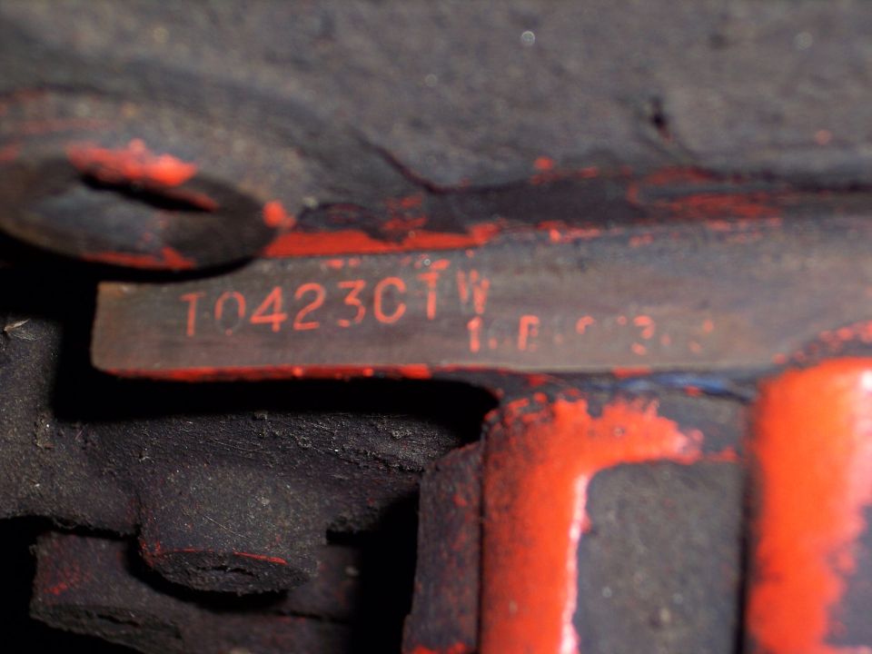 Close-up of red engine block with stamped numbers T0423CTW and 1.F.R.3