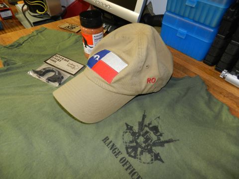 1996 Ford Bronco - A collection of items including a Texas-themed cap and a 'Range Officer' t-shirt are laid out on a wooden surface.