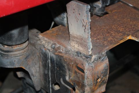 1990 Ford Bronco - This photo shows a close-up view of a welded metal bracket on a vehicle's frame, with visible rust and a red component above.