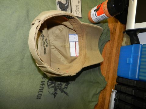 1996 Ford Bronco - A tan baseball cap rests on a green t-shirt with printed text and graphics.