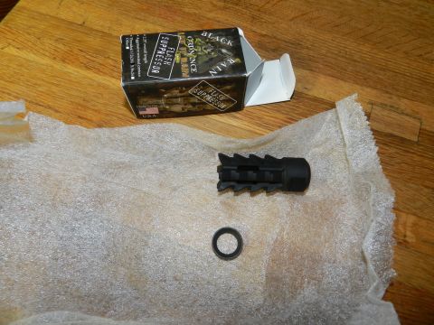1996 Ford Bronco - A black flash suppressor and its packaging are displayed on a wooden surface.